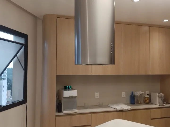 Coifa cilíndrica em aço inox instalada sobre cooktop em ilha em cozinha gourmet