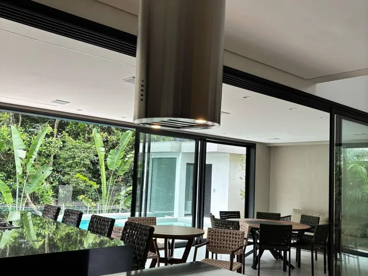 Coifa redonda em aço inox suspensa sobre ilha em ambiente gourmet integrado
