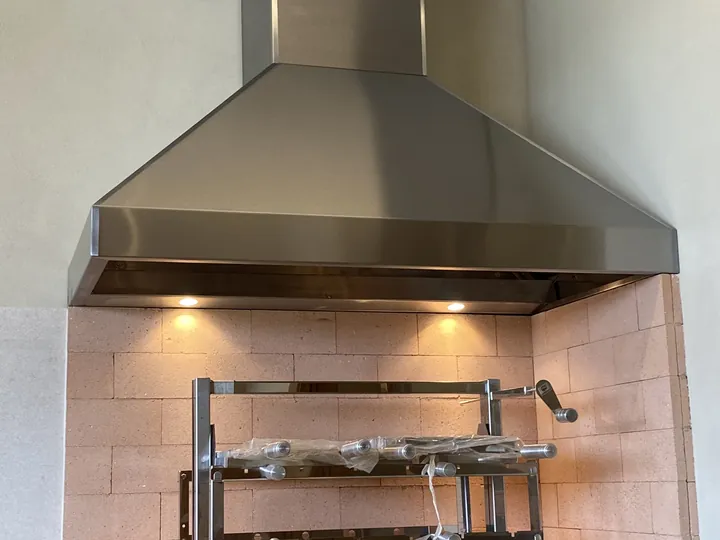 Coifa 3 águas sob medida instalada sobre parrilla em espaço gourmet