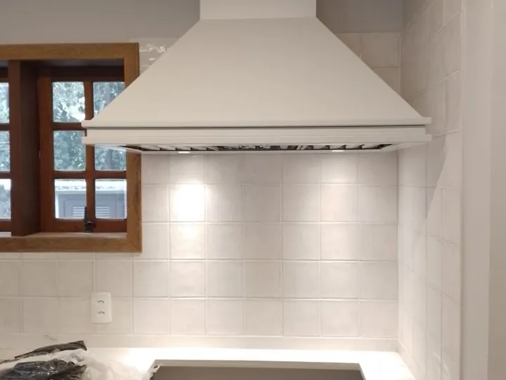 Coifa personalizada de parede com acabamento branco em cozinha residencial