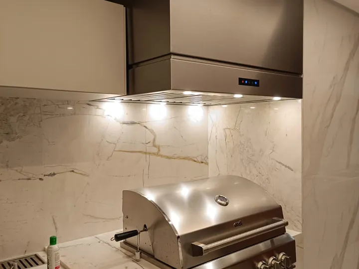 Coifa para churrasqueira a gás sob medida com iluminação em cozinha gourmet.